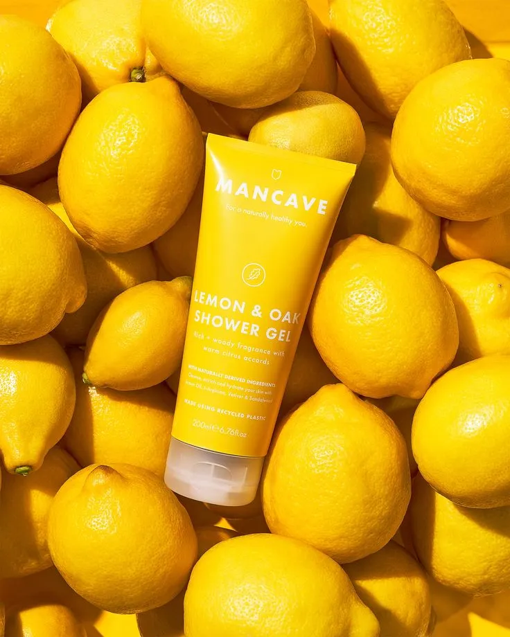 Tube de gel douche Mancave Lemon & Oak posé sur un lit de citrons jaunes
